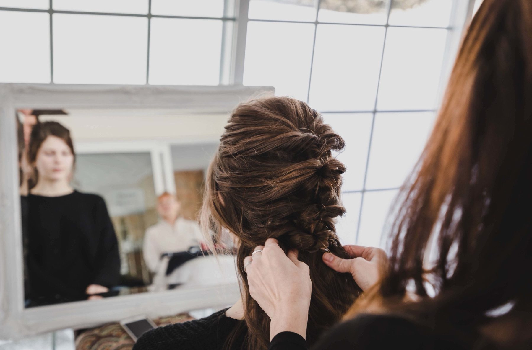 Bride's hair being styled in front of a mirror