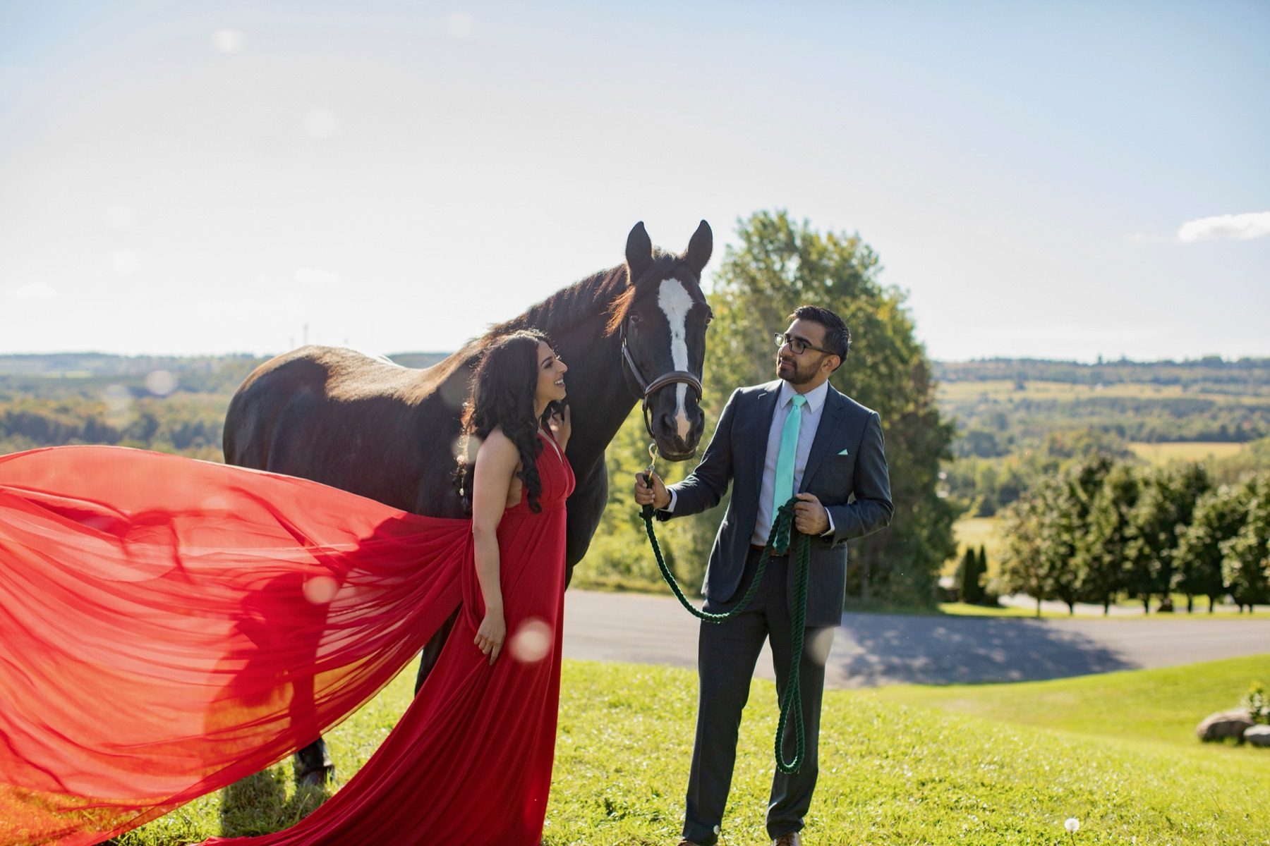 Bride in red gown beside a bay horse
