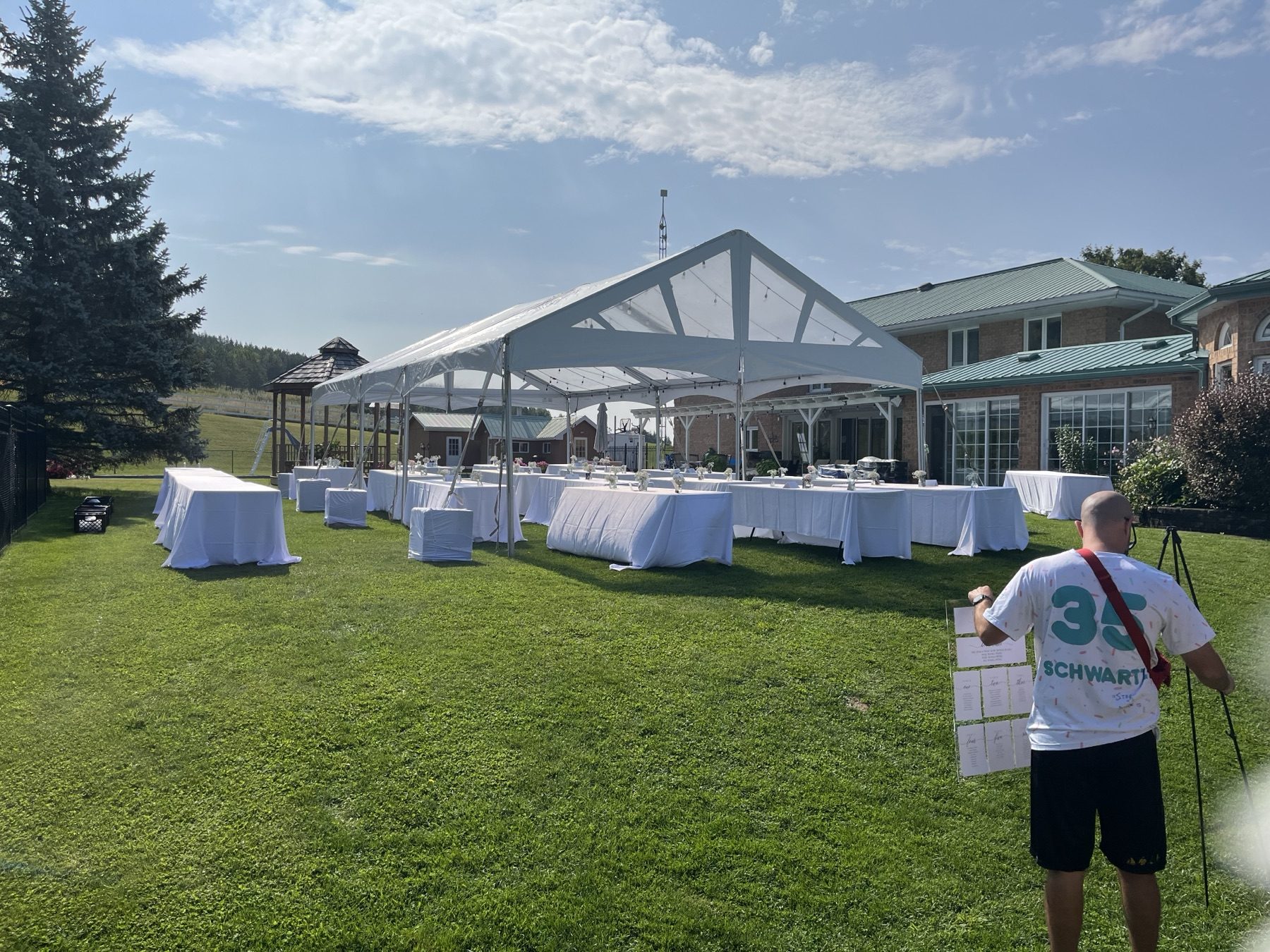 Large open-sided tent set up on the lawn with long banquet tables
