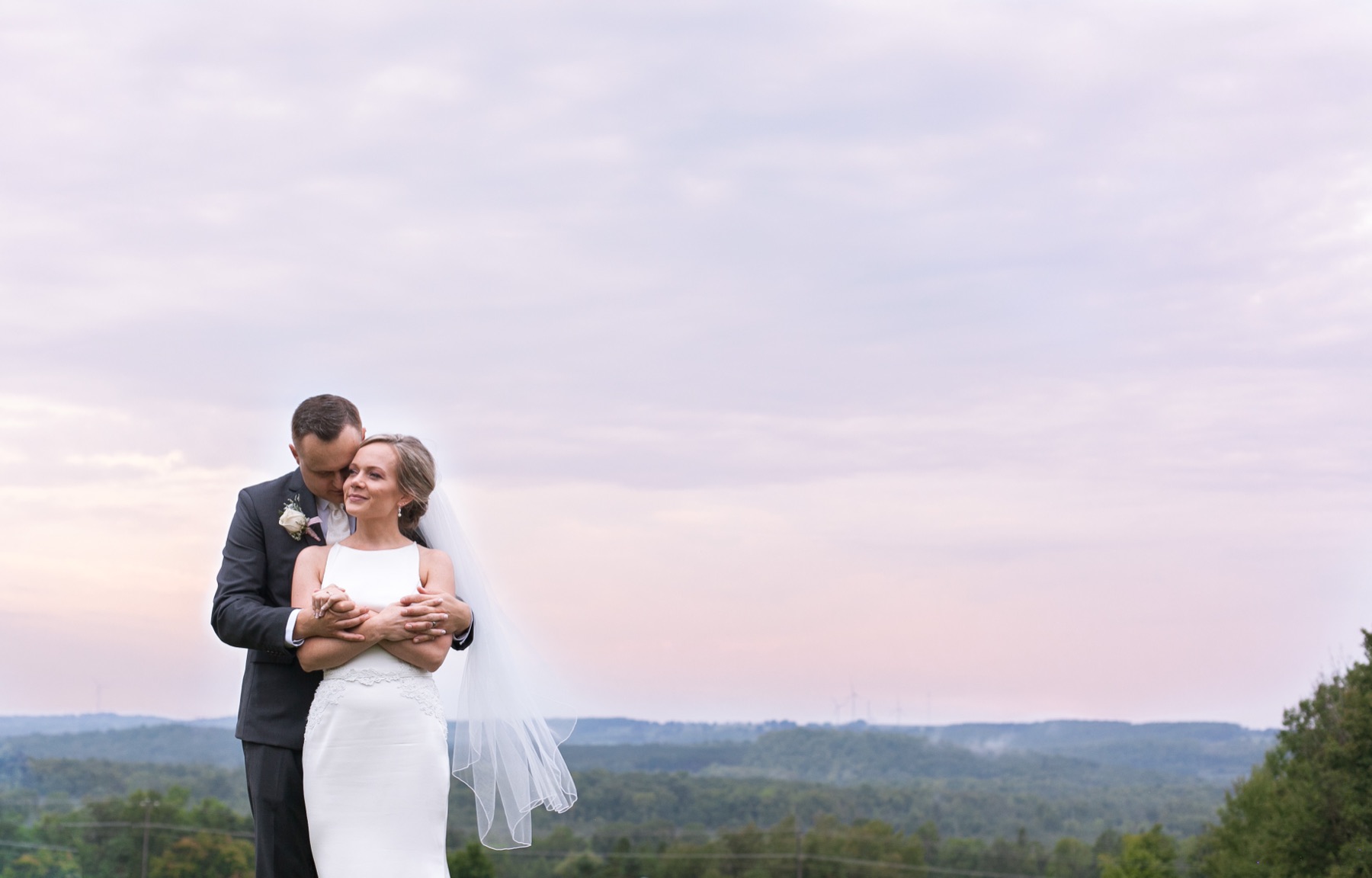 Couple embracing at dusk with hills in background