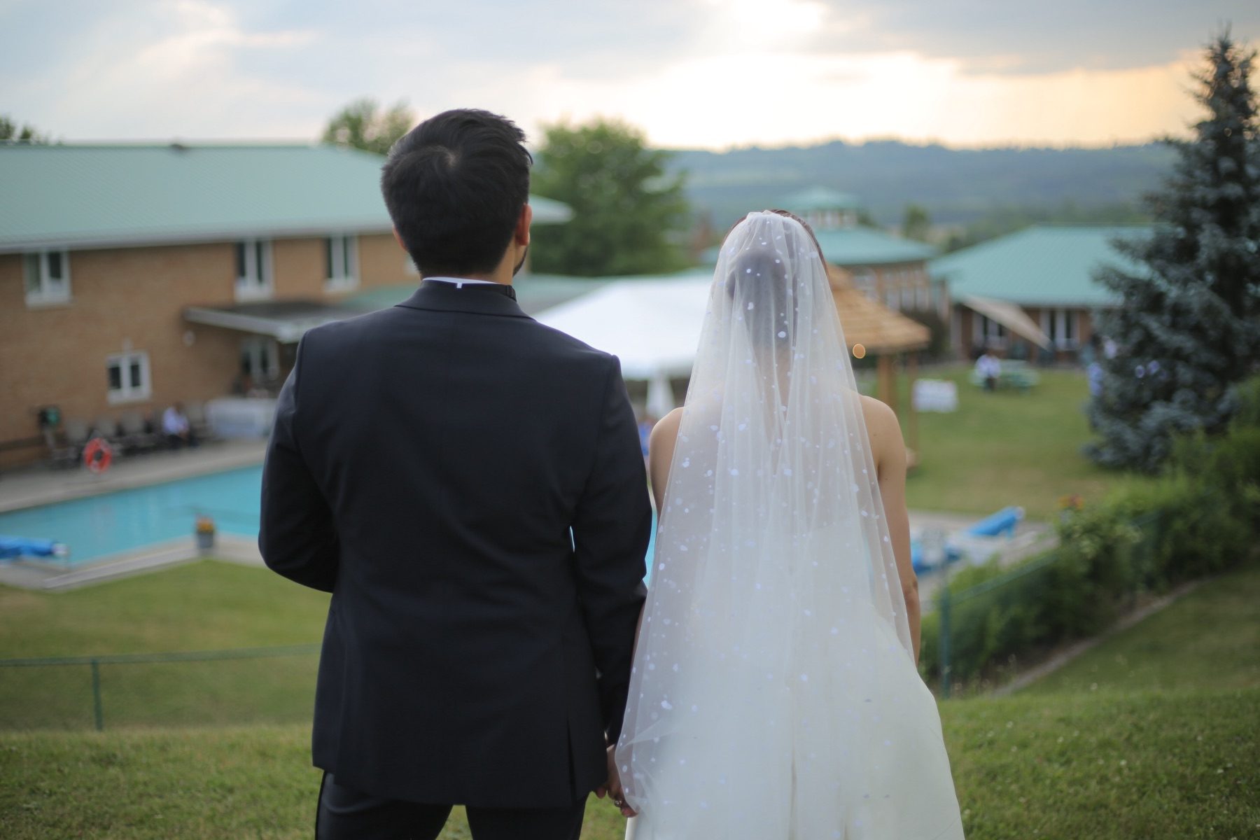 Couple from behind looking over the pool and grounds at dusk